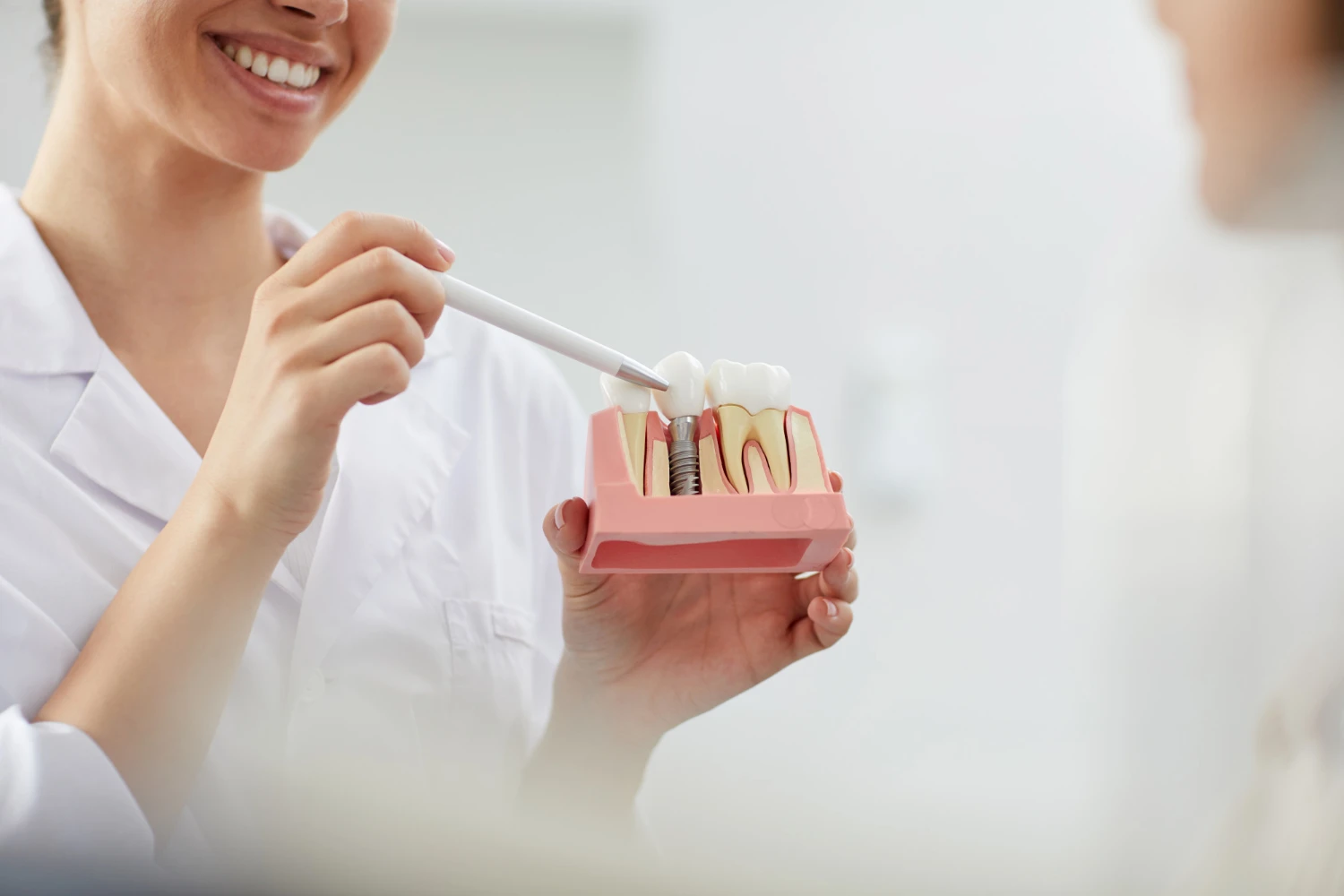 Dentist pointing to an implant teaching model held in one hand