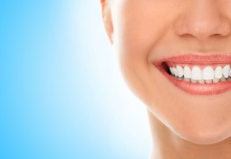 Close-up of a woman's smile on a blue background with bright front teeth