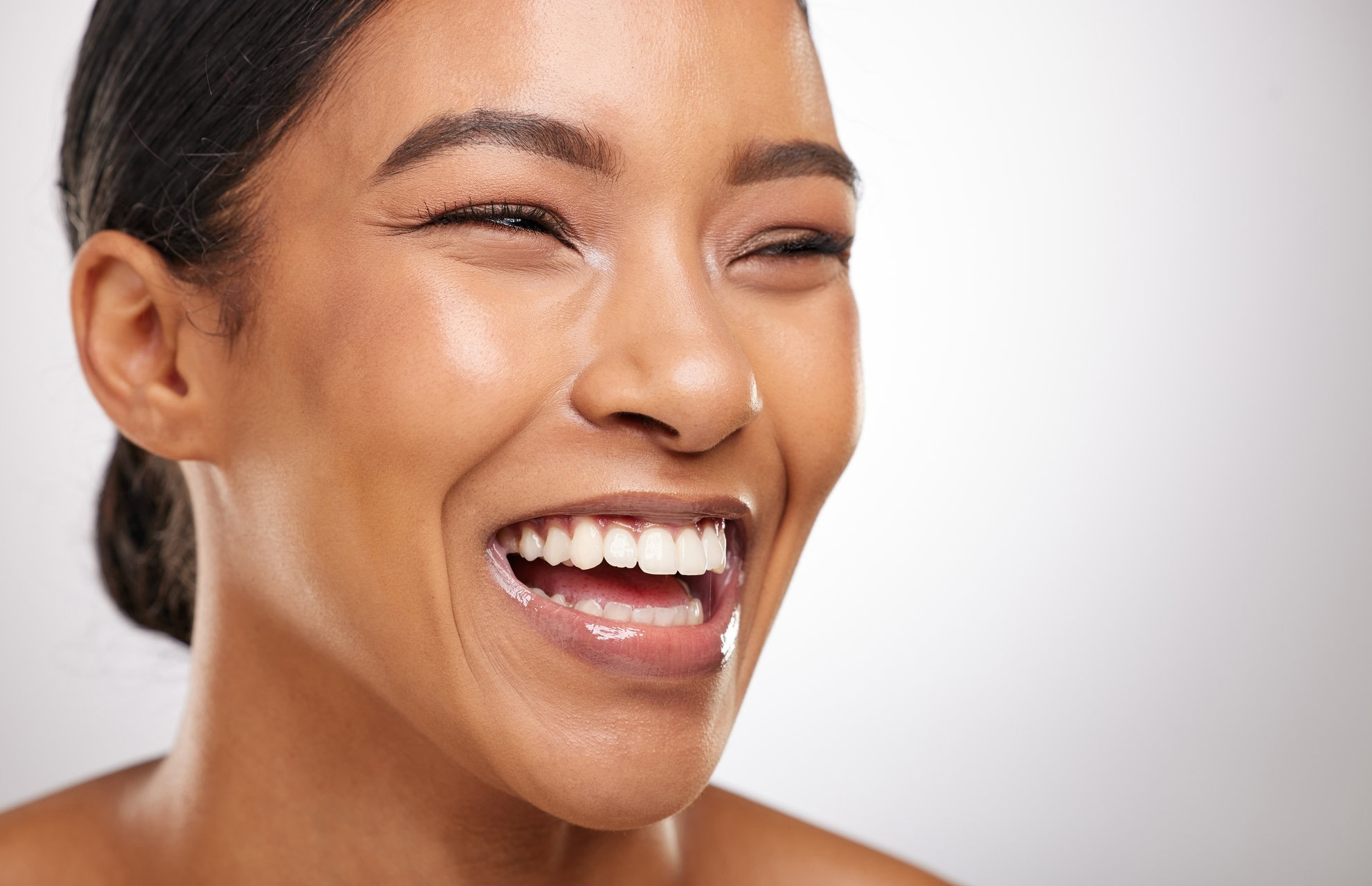 Woman laughing on a light background with her upper front teeth showing