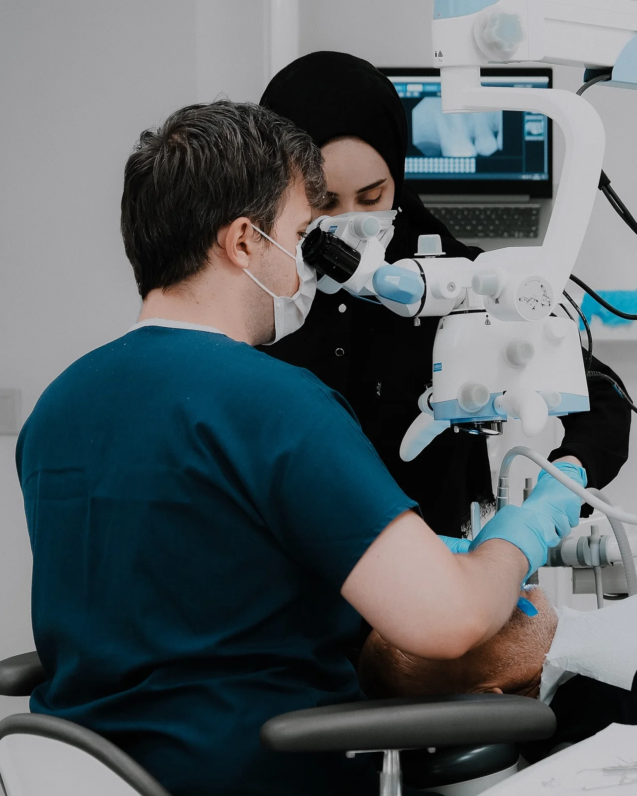 Root canal treatment under the dental microscope: clinician at the scope, periapical image on screen